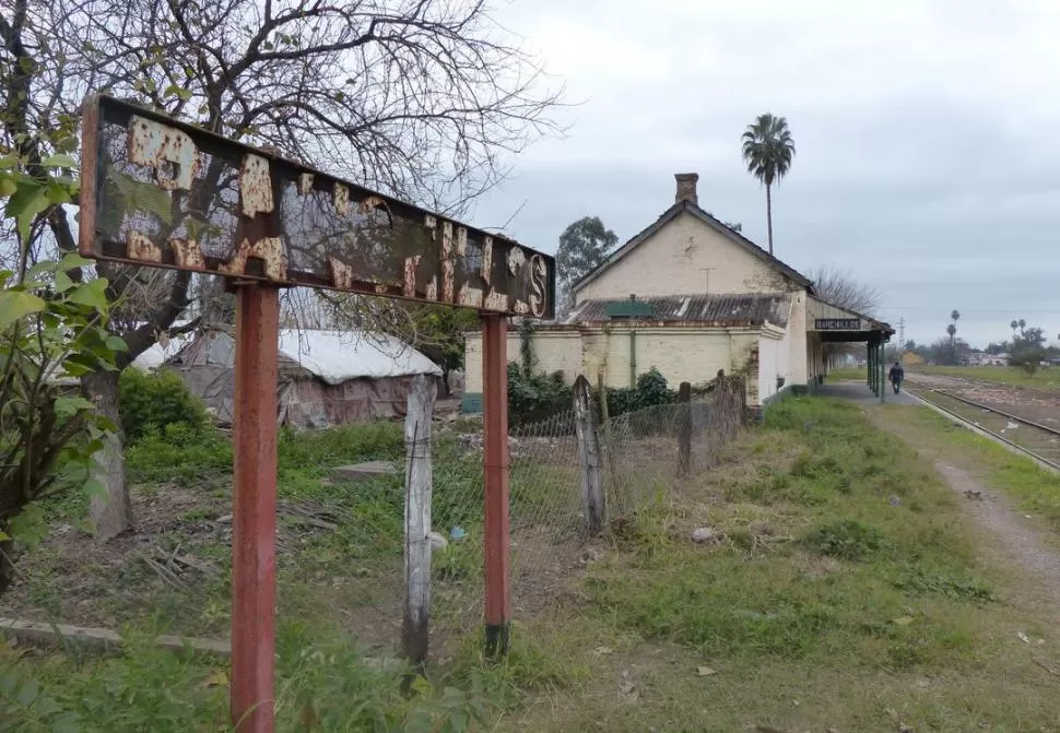 SIMBOLO DE ACTIVIDAD. El cartel apenas es legible. Una senda entre el pasto del andén hizo desaparecer el piso. Los escombros abundan entre las vías. Hace 21 años por acá pasaban mas de cinco formaciones diarias. 