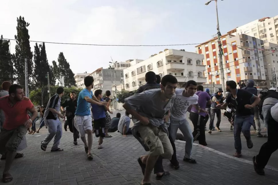 HUIDA PRESUROSA Y DESORDENADA. Palestinos residentes de la ciudad de Gaza corren en busca de un lugar donde ponerse a cubierto, durante un ataque de la aviación y de la artillería israelí. fotos reuters