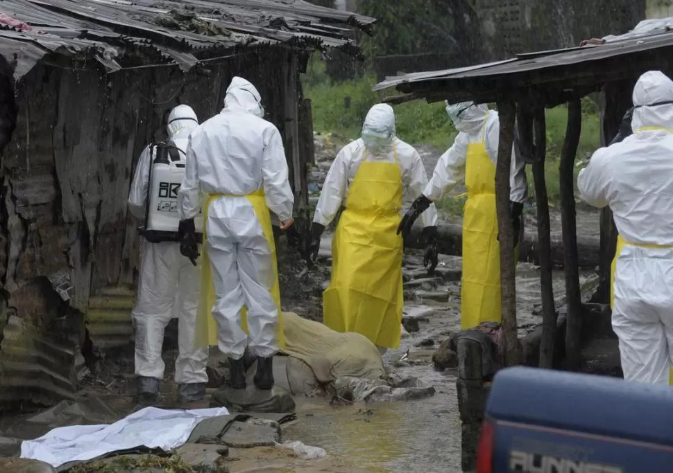 LIBERIA. Enfermeros cubren un cadáver abandonado en la calle. reuters