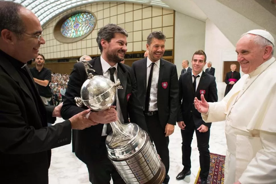 ES SUYA TAMBIÉN. Lammens, Tinelli y Buffarini le hacen entrega de la réplica de la Copa Libertadores al Papa Francisco durante la audiencia pública que se llevó a cabo ayer en el Vaticano. 