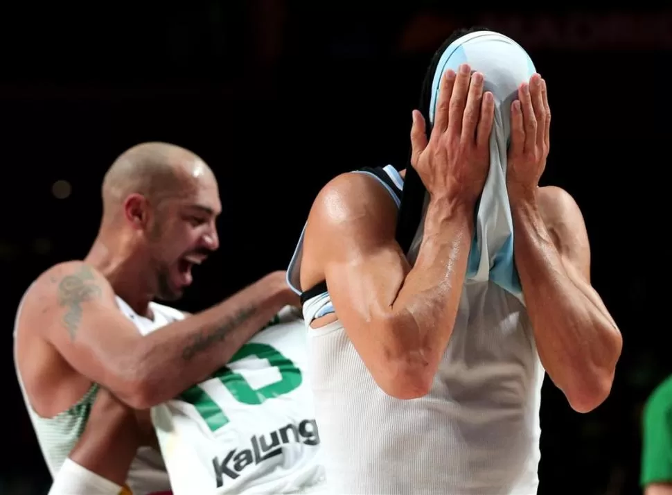 PESADILLA. Scola cubre su rostro con la camiseta y sus manos; en el fondo, los jugadores brasileños festejan la victoria.  FOTO DE fiba.com