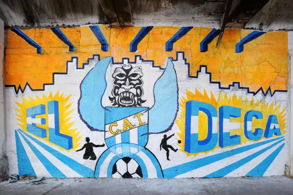 ATLÉTICO Y LA CIUDAD. Ávila dejó casi terminado su mural a mitad de calle Laprida en el que puede apreciarse el panorama de la urbe y una criatura con alas y el torso hecho con el escudo de Atlético.   