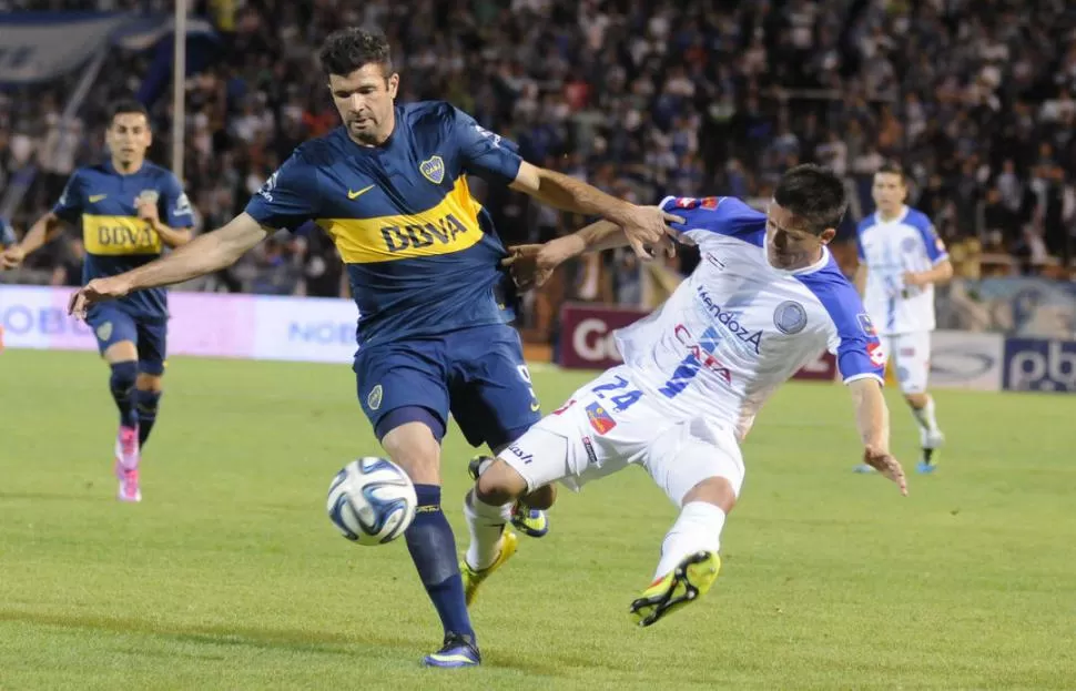 PUDIERON FRENARLO. García Guerreño, autor del primero gol del “tomba”, marca a Gigliotti, bien contenido por él y el resto de los defensores de Godoy Cruz.  