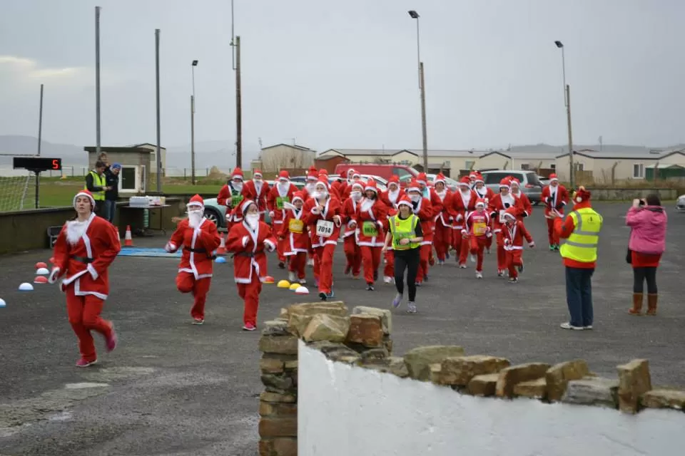 EN IRLANDA. Personas de diferentes edades corren por una calle de la localidad de Galway disfrazadas como Papá Noel mientras los filman y les sacan fotos. partyearth.com