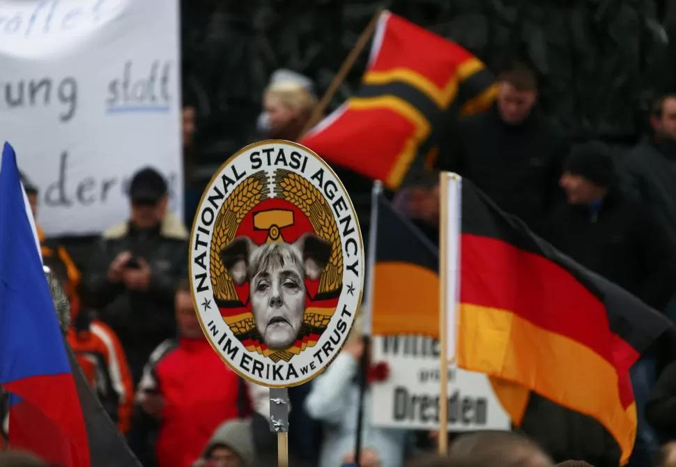 CONTRA MERKEL. Los manifestantes de Pegida muestran una pancarta con una caricatura de la canciller. reuters  