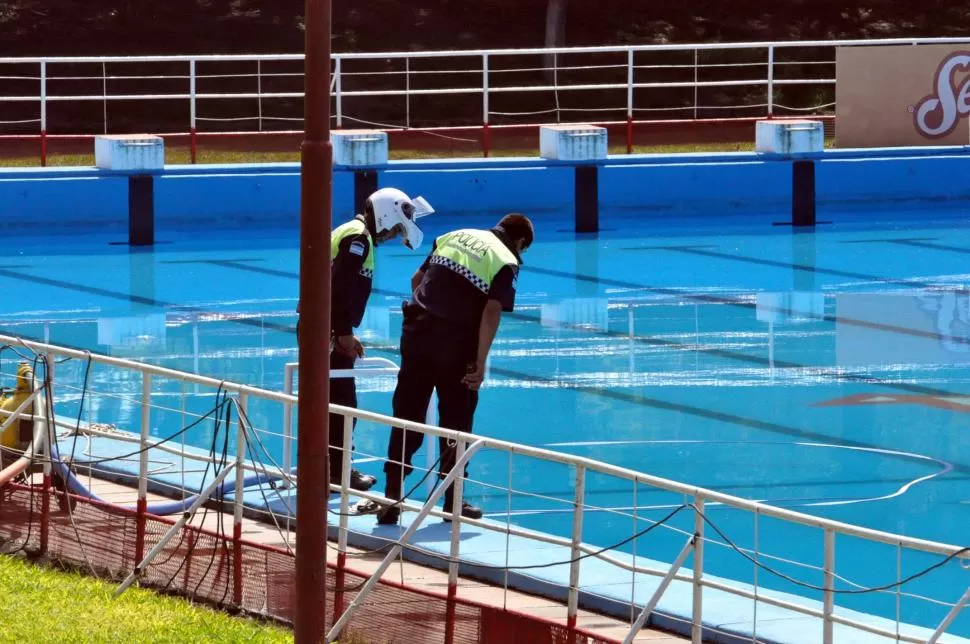 EN LA PISCINA. Dos policías observan el lugar donde habría sido recuperado el cuerpo del adolescente. FOTO GENTILEZA JOSÉ A. DÍAZ ROMERO