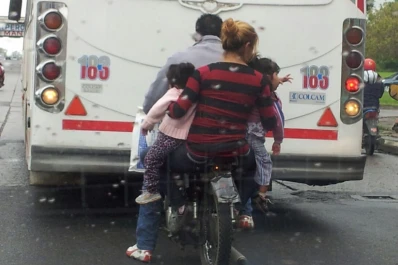 Una mujer lleva colgando a dos menores de una moto