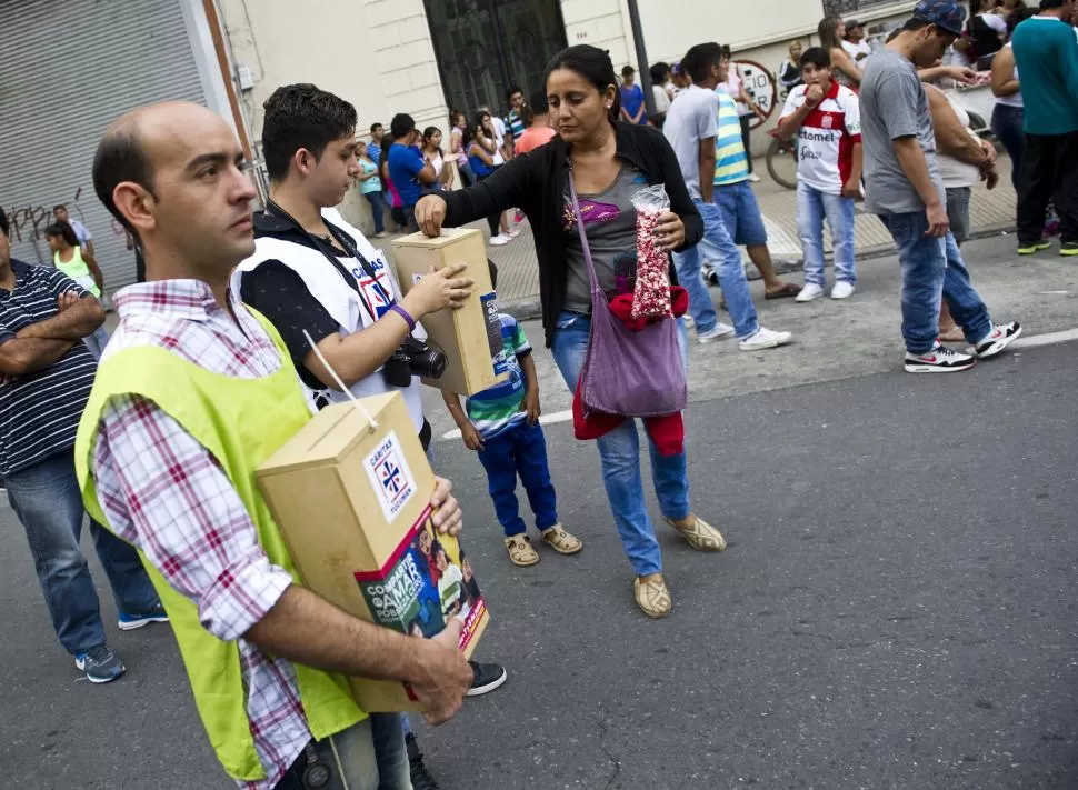 AYUDA. Una mujer deja dinero en la urna de un voluntario de Cáritas. 