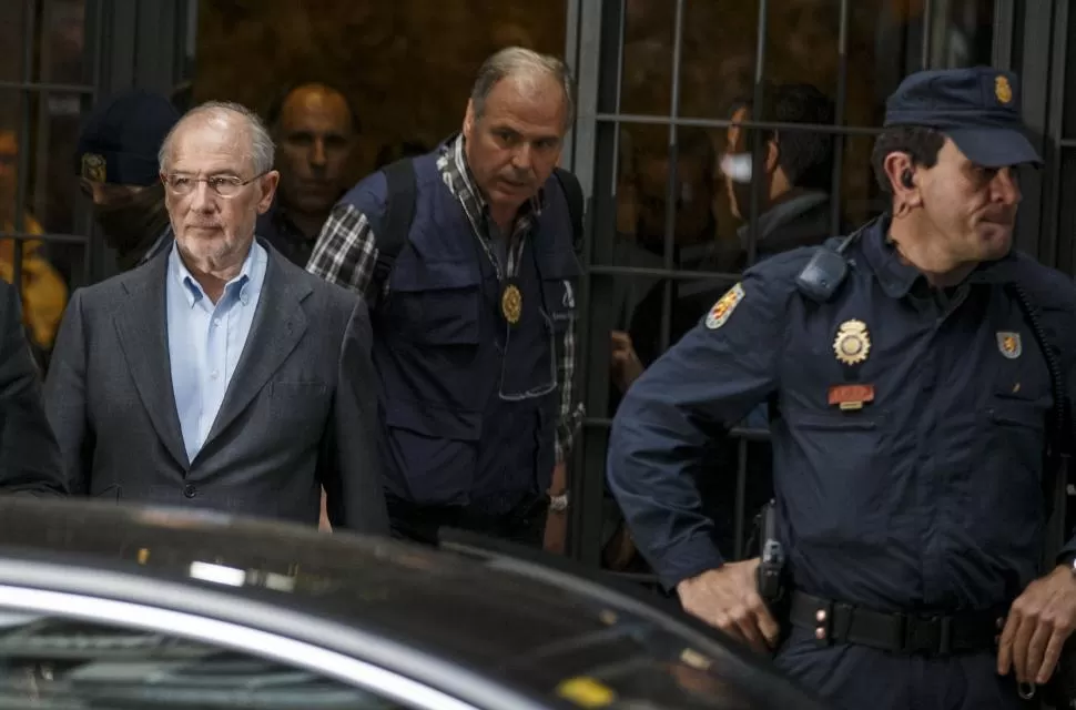 AL JUZGADO. Rodrigo Rato, de anteojos, sale de su casa en Madrid, escoltado por los policías que la allanaron. reuters