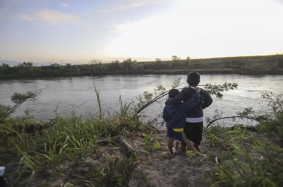EL CAUCE, AYER. Dos hermanitos contemplan abrazados el caudal del río Chico, idéntico al que registra el video enviado a LA GACETA, que las autoridades educativas consideran de 2014. LA GACETA / FOTO DE Osvaldo Ripoll 