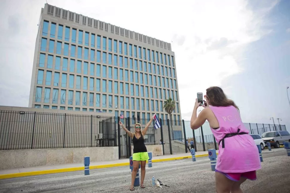 POSTAL. Turistas estadounidenses se toman fotos ante la sede de la embajada de su país en La Habana. Allí comenzará a ondear la bandera de EEUU. reuters