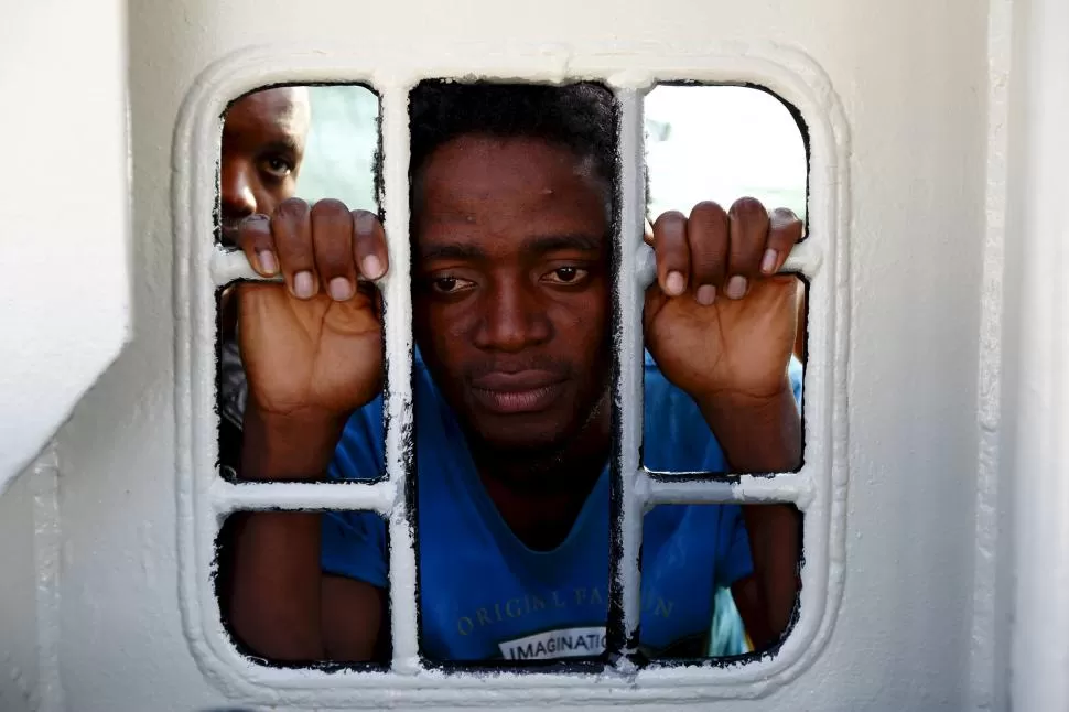 EN SICILIA. Inmigrantes miran por la venta del barco que los socorrió en alta mar, mientras navegan a Trápani. reuters