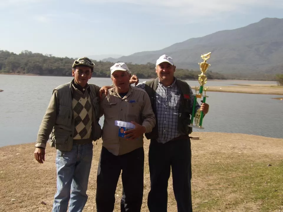 FESTEJOS. Carlos Nieva -con el trofeo- recibe el saludo de Víctor Rueda y Armando Miranda, sus compañeros de equipos. foto de club caza y pesca unt