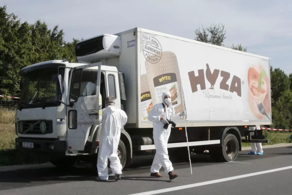 EN PANDORF. La policía austríaca inspecciona el camión frigorífico abandonado en la ruta, donde encontraron unos 50 cadáveres de inmigrantes. reuters