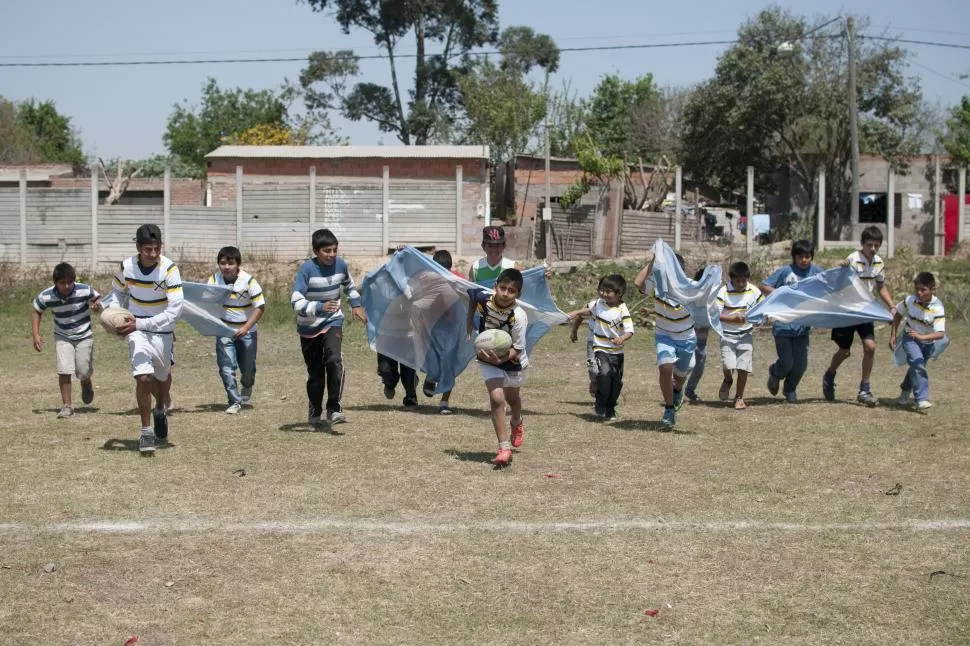 CARRERA A LA GLORIA. Con el orgullo de ser de Villa 9 de Julio, los jóvenes jugadores corren hacia el ingoal a toda velocidad. A sus espaldas, las casas en donde viven custodian cada entrenamiento. la gaceta / foto de inés quinteros orio