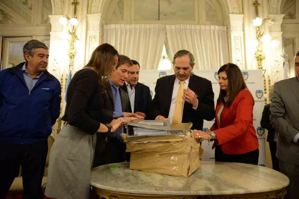 PLIEGOS. Alperovich (centro) abre los sobres, ante la mirada de funcionarios. prensa y difusión
