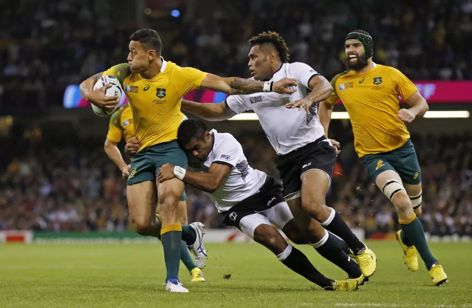 SÓLO DE A DOS LO FRENAN. El australiano Israel Folau se aferra a la ovalada con la intensa presión de los potentes fijianos Asaeli Tikoirotuma y Metuisela Talebula. REUTERS