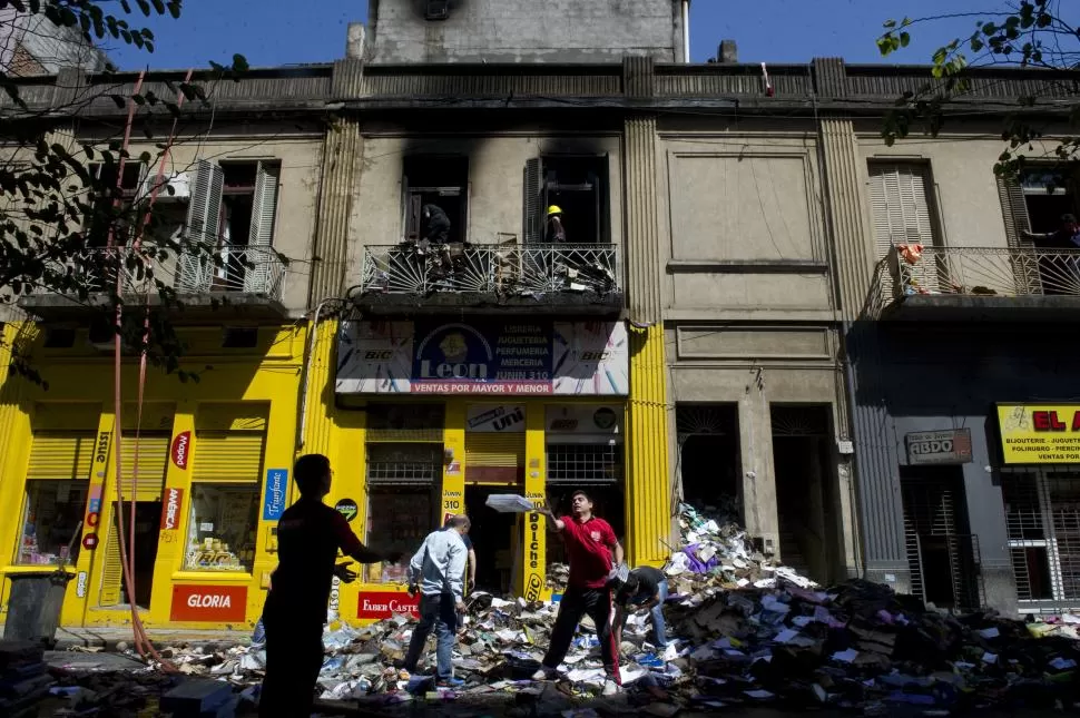 LIMPIEZA. Empleados de la librería “León” comenzaron ayer a sacar toda la mercadería que estaba almacenada en los depósitos donde comenzó el incendio que consumió el local.  la gaceta / fotos de jorge olmos sgrosso