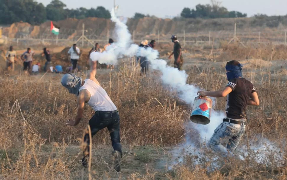 GAZA. Un palestino devuelve una bomba de gas lanzada por el ejército. reuters