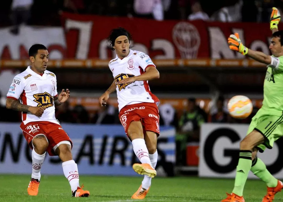 NO LO DEJÓ NI ACOMODARSE. Patricio Toranzo, acompañado por Daniel Montenegro, aprovechó una mala salida de Marcelo Barovero para anotar el primer gol de Huracán cuando recién comenzaba el partido. telam