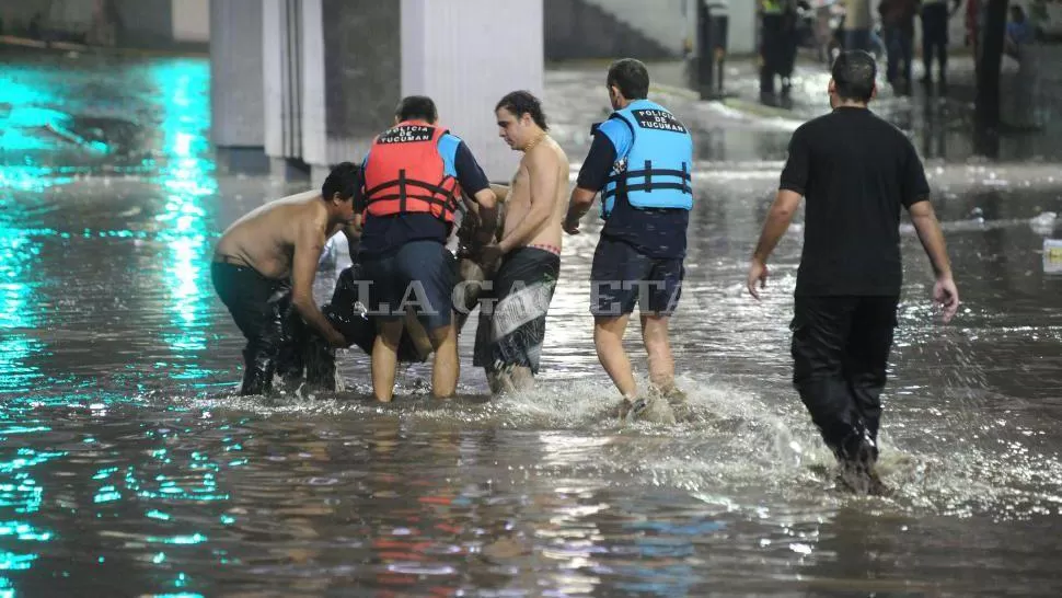 DURA TAREA. Automovilistas, transeúntes y policías sacan el cuerpo de Hipólito Brozoski, que había sido arrastrado hacia una boca de desagüe. LA GACETA / FOTO DE HÉCTOR PERALTA