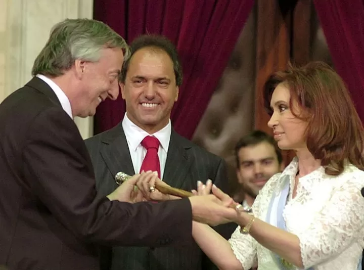 POSTAL DE 2007. Kirchner le entrega el bastón de mando a Cristina. Scioli, ex vice de Néstor, los observa y sonríe. perfil.com