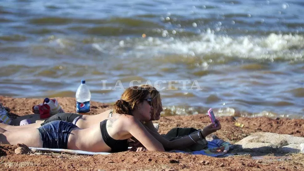 REFUGIO. Algunos eligieron las playas del dique El Cadillal para mitigar la calurosa jornada. LA GACETA  