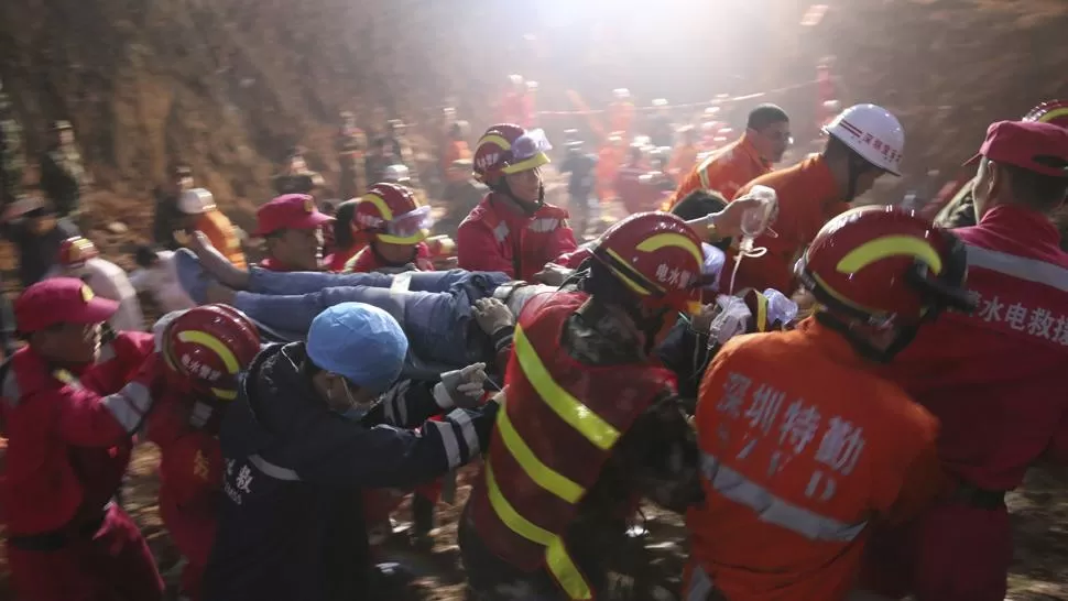 HALLAZGO. Los rescatistas se apresuran en sacar al joven de los escombros. REUTERS