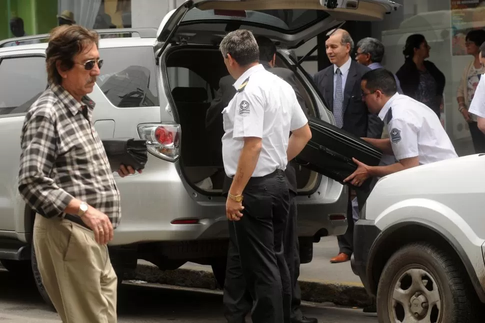 EN PLENA “CITY”. Dos policías escoltan a empleados de la Legislatura, y ayudan a cargar las valijas con millones para gastos sociales en la camioneta oficial. la gaceta / foto de inés quinteros orio (archivo)