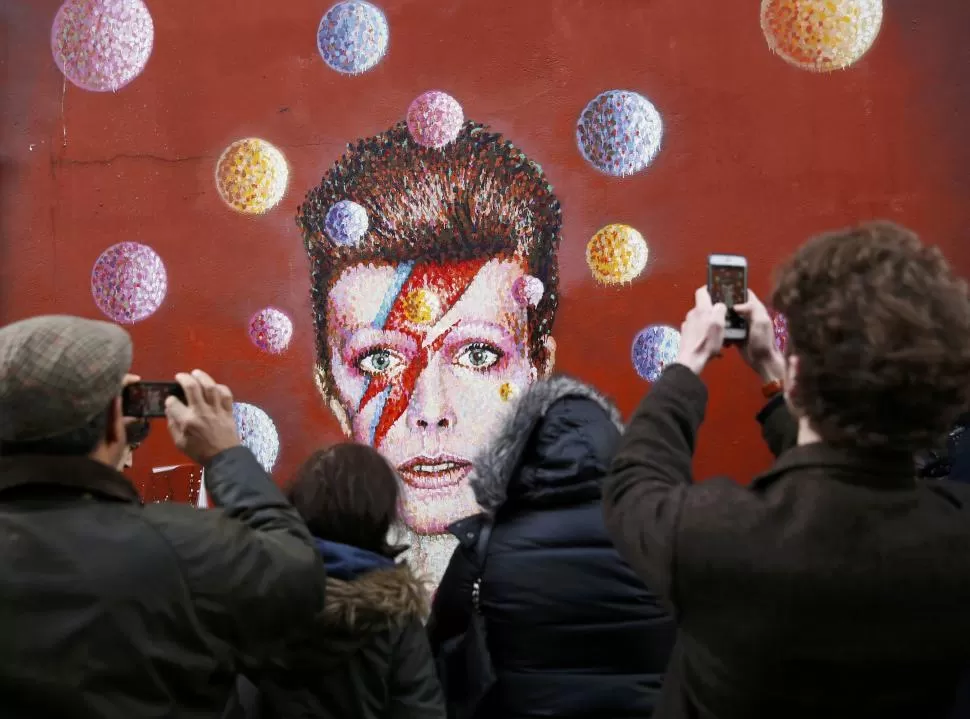 ADIÓS A LA ESTRELLA. Fanáticos le rindieron homenaje a Bowie frente a un mural que reproduce una de su tantas transformaciones. reuters