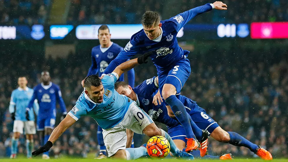 A MANO. Así quedaron Manchester City y Everton. Sergio Agüero trata de mantener la posesión de la pelota desde el piso.
FOTO DE REUTERS