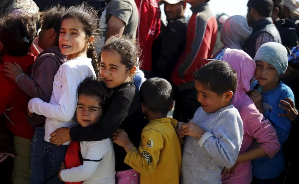 EN IDOMENI. Niños y adultos hacen cola para recibir sus alimentos. reuters 