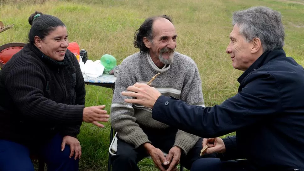 JUNTO A LA RUTA. Macri, con el vendedor de bollos y su esposa, DYN