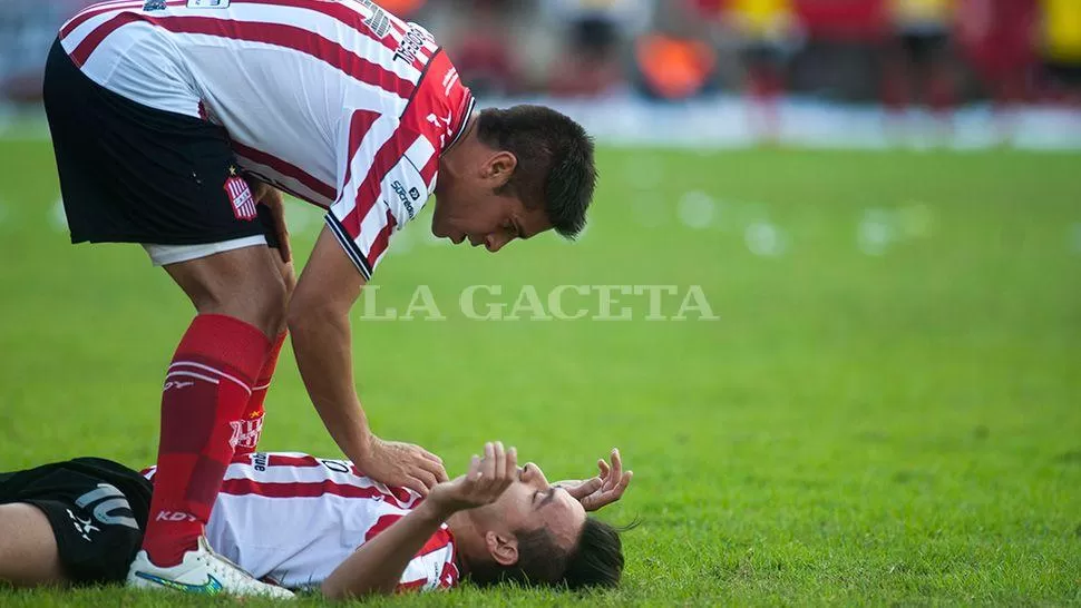 ASISTENCIA. Luciano González junto a Sergio Viturro, tendido en el césped. LA GACETA / FOTO DE DIEGO ARÁOZ