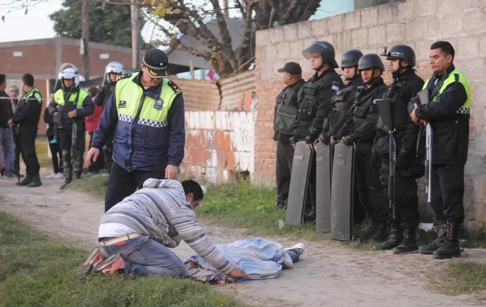 DOLOROSA POSTAL. Un familiar del recluso asesinado abraza el cuerpo mientras los uniformados tratan de mantener el orden en el lugar. la gaceta / fotos de hector peralta