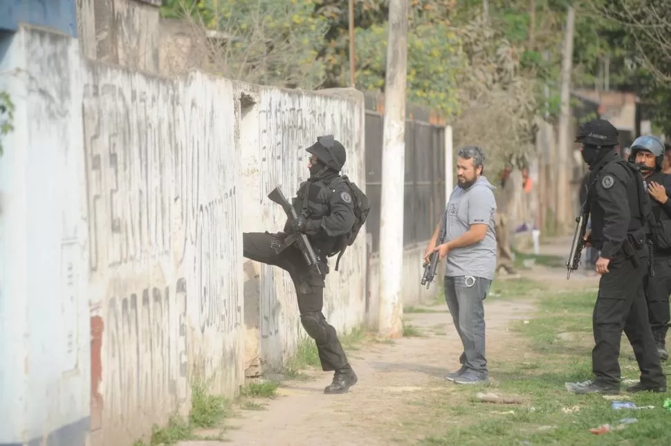 PATEANDO PUERTAS. Un policía ingresa a una vivienda en busca de un joven que intentaba huir del lugar. la gaceta / foto de diego aráoz