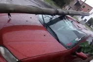 A causa del fuerte viento, un poste de teléfono destruyó un auto