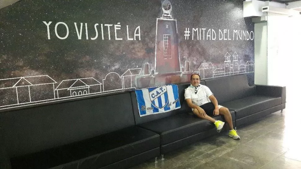 DE TURISTA. Manuel Velárdez posa con la bandera de Atlético en el Paralelo que divide al planeta tierra en dos hemisferios; luego irá a Colombia para alentar al “Deca”.  