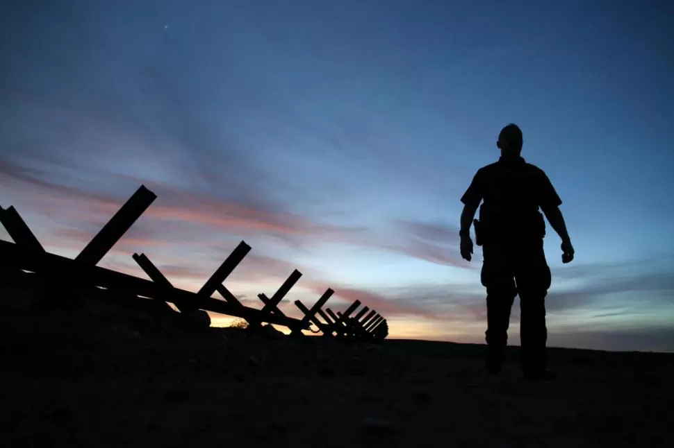 A LA ESPERA DE LA MURALLA. Un agente de la patrulla fronteriza de EEUU realiza un control en una de las vallas que separa a California de México. Reuters