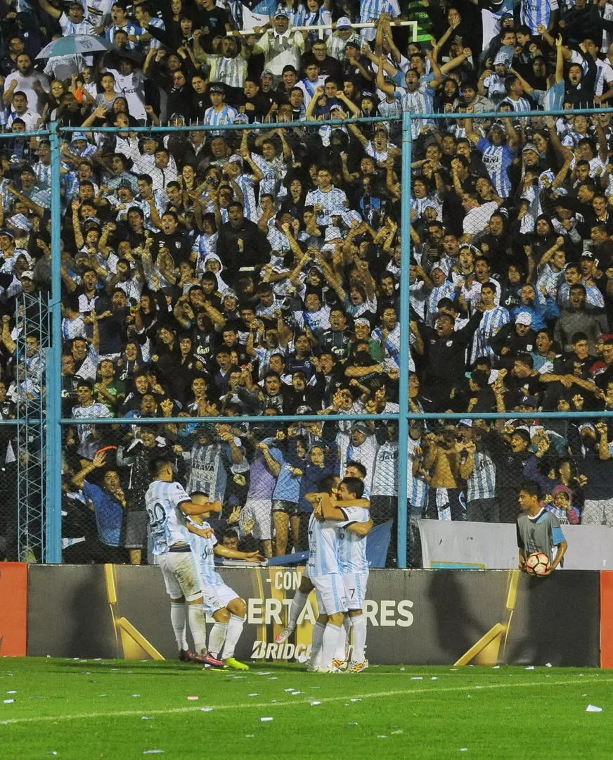 SONRISAS. Dentro del campo de juego, los jugadores se abrazan para celebrar el gol. Afuera, en las tribunas, los hinchas estallan de felicidad. Atlético ganó y sigue con chances de clasificar a octavos de final. la gaceta / foto de hector peralta