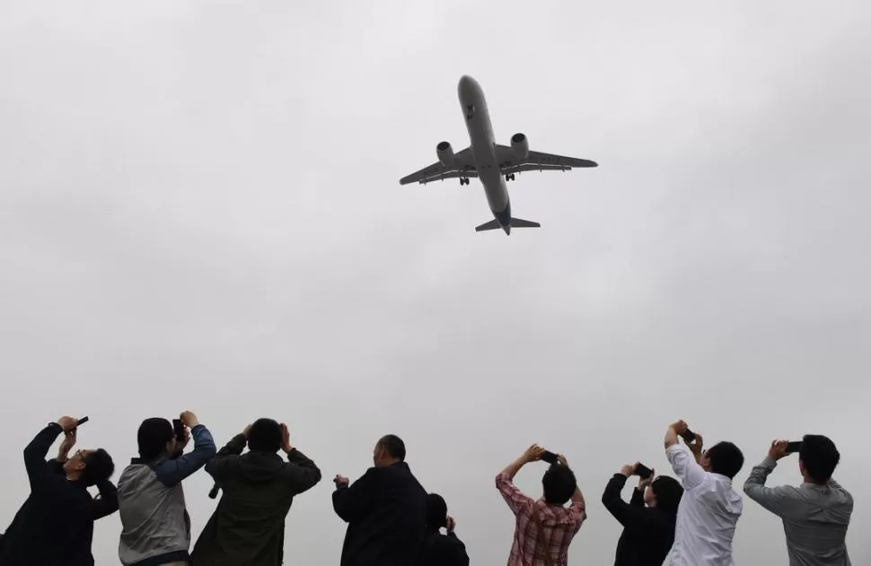 VUELO INAUGURAL. Los chinos saludan la aeronave de fabricación propia. reuters