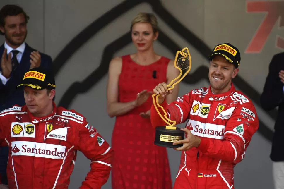 LOS ROSTROS HABLAN. Kimi Räikkönen mira a la nada, con gesto adusto en la ceremonia del podio; Sebastian Vettel no cabe en su buzo de la alegría por el éxito. prensa ferrari 