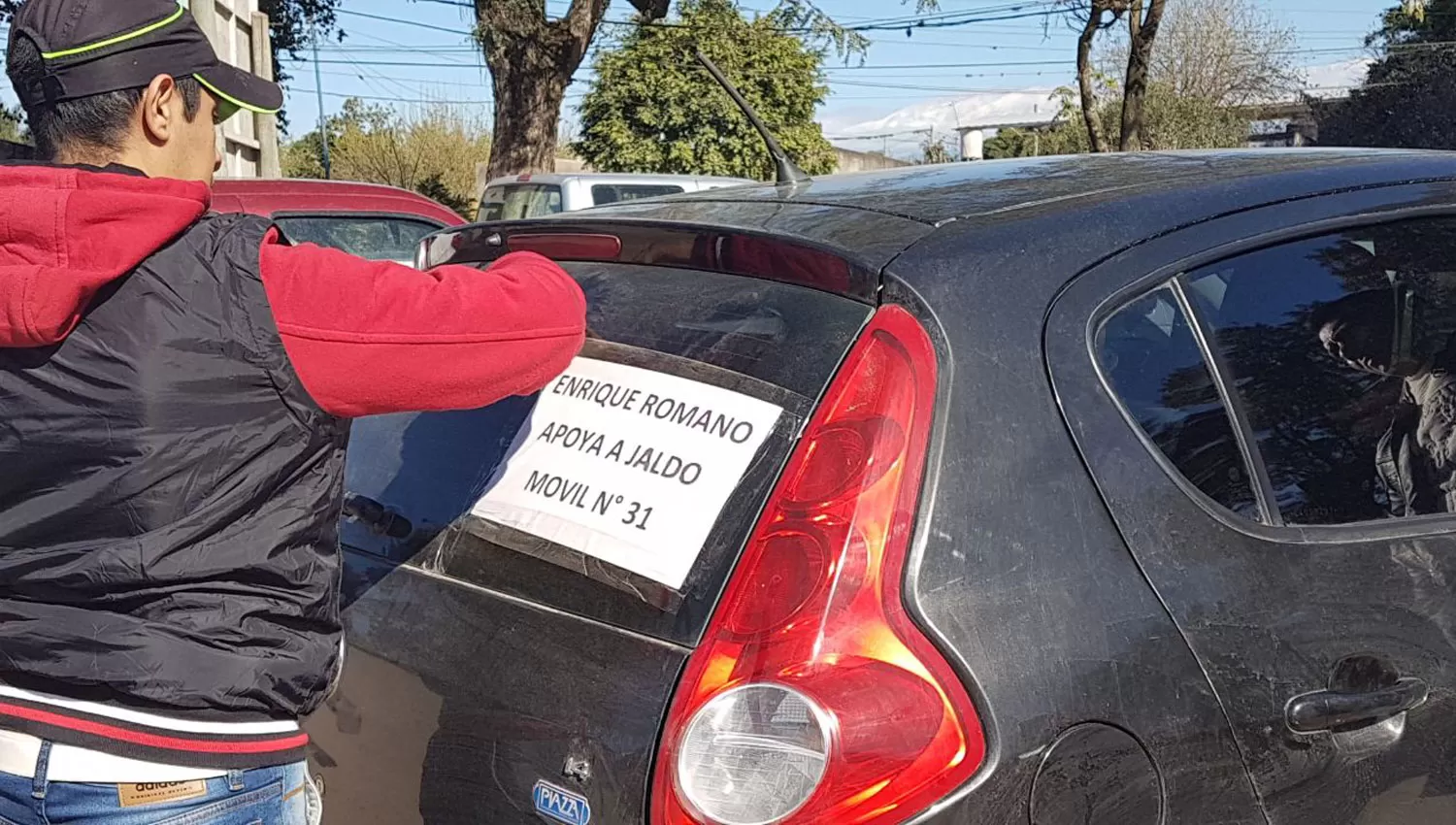 MOVILIZACIÓN. El chofer de un auto le quita el cartel que identifica al dirigente que lo habría contratado. LA GACETA / NATALIA VIOLA