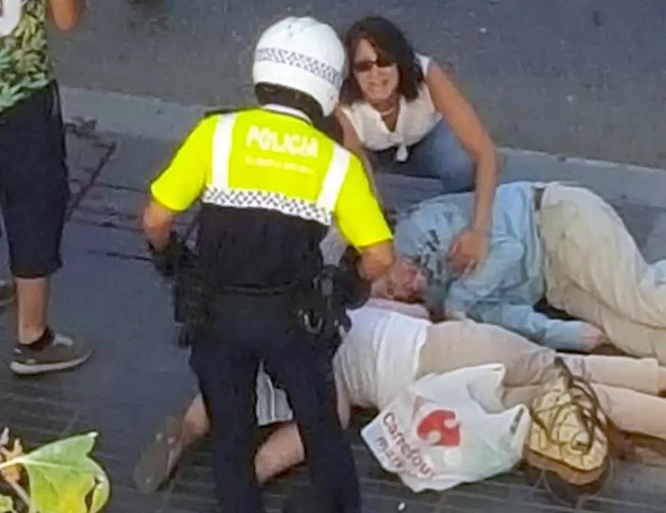 DRAMATISMO. Un policía y una transeúnte tratan de socorrer a dos personas mayores que resultaron heridas y yacen en la acera. fotos Reuters