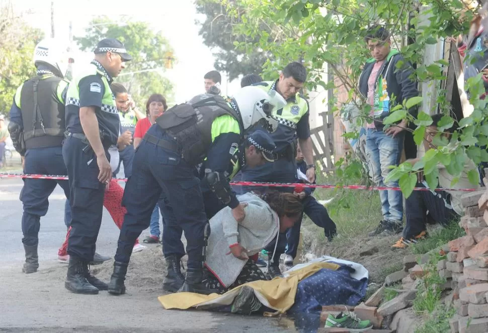 DESESPERACIÓN. La hermana de la víctima se acerca al cuerpo, contenida por los policías. la gaceta / foto de antonio ferroni
