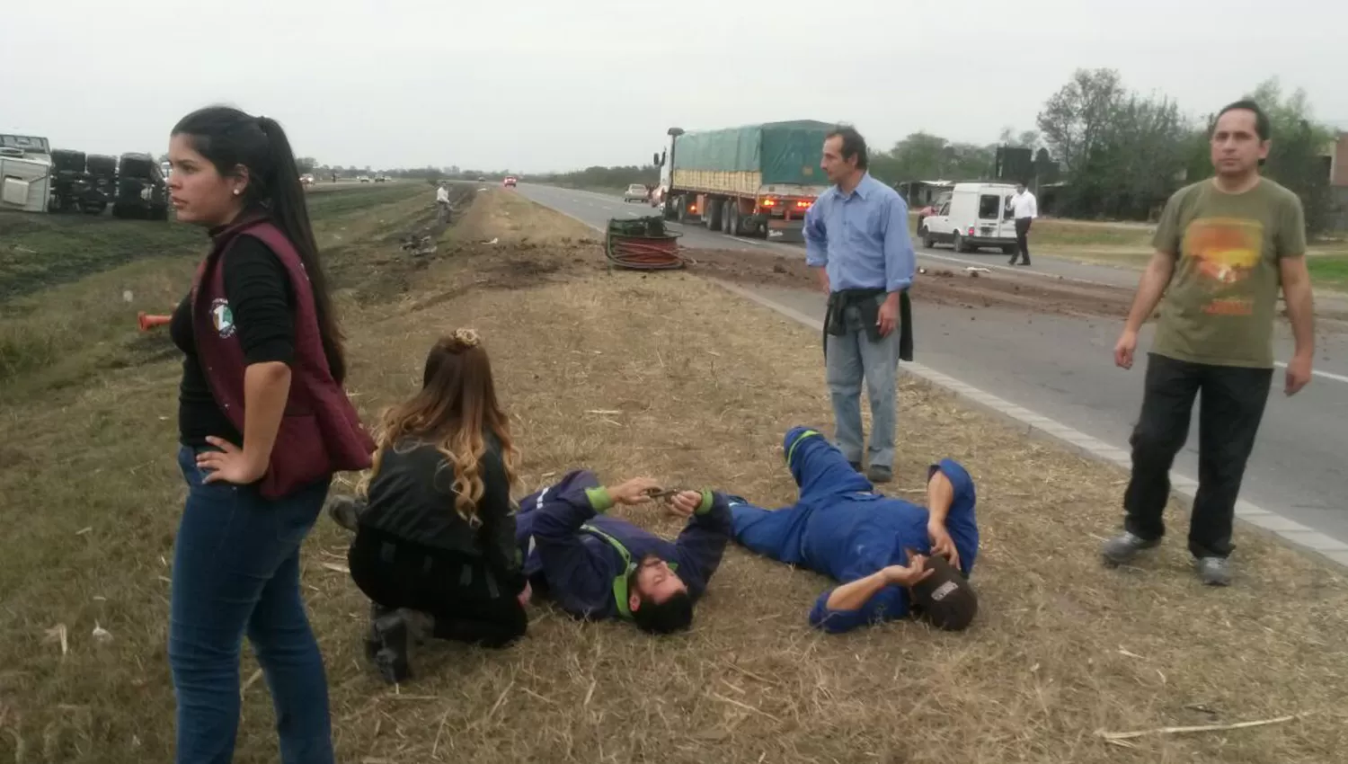 LESIONES LEVES. Dos de los ocupantes del camión volcado esperan los primeros auxilios. FOTO ENVIADA POR UN LECTOR