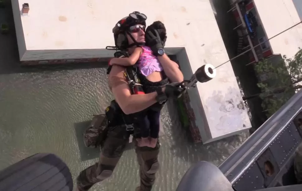 HOUSTON. Un rescatista lleva a un niño que estaba atrapado en su casa.   fotos de Reuters