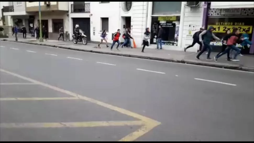 PERSEGUIDOS. Una decena de alumnos escapa de un efectivo motorizado que los persigue por una vereda de Barrio Norte, ante la impávida mirada de los transeúntes. Tras el violento episodio, hubo nueve demorados en la comisaría 1°. 