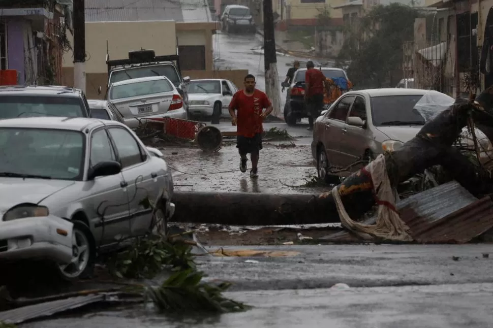 ZONA DEVASTADA. Un hombre corre por una calle azotada de Guayama. reuters