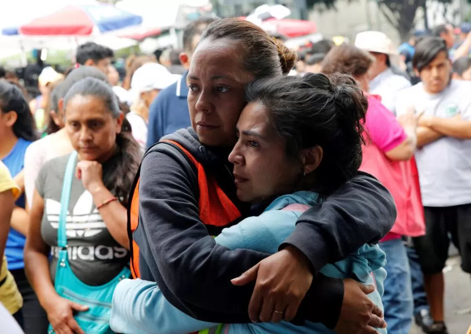 PLEGARIAS Y CONSUELO. Fieles escuchan la homilía durante una misa en una calle de la ciudad de México. reuters